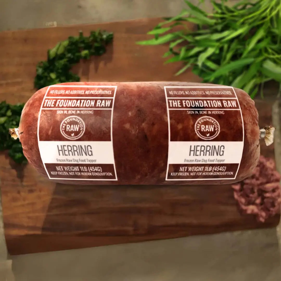 Rolled herring with 'The Foundation Raw' labels on a wooden surface. ground herring dog food roll ground herring raw food diet for dogs raw dog food raw dog food roll fish for dog fish meat
