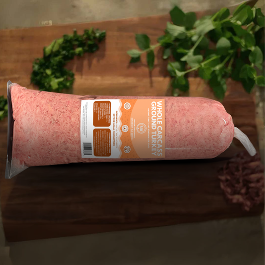 Rolled ground turkey package on a wooden surface with greenery in the background