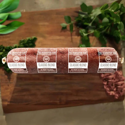 Roll of Classic Blend on a wooden surface with greenery in the background classic blend raw beef dog food beef muscle meat ground bone beef muscles raw food diet for dogs raw dog food raw dog food roll