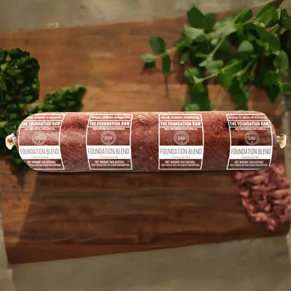 Rolled raw meat product on a wooden surface. foundation blend raw beef dog food beef muscle meat green tripe beef liver beef kidney beef spleen raw food diet for dogs raw dog food raw dog food roll