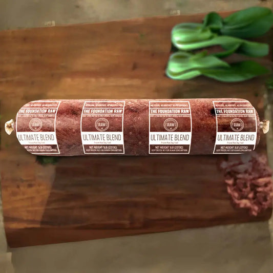 Rolled meat product with 'The Foundation Raw' labels on a wooden surface ultimate blend raw beef dog food  ground bone beef muscle meat green tripe beef liver beef kidney beef spleen pollock raw food diet for dogs raw dog food raw dog food roll dog food chub